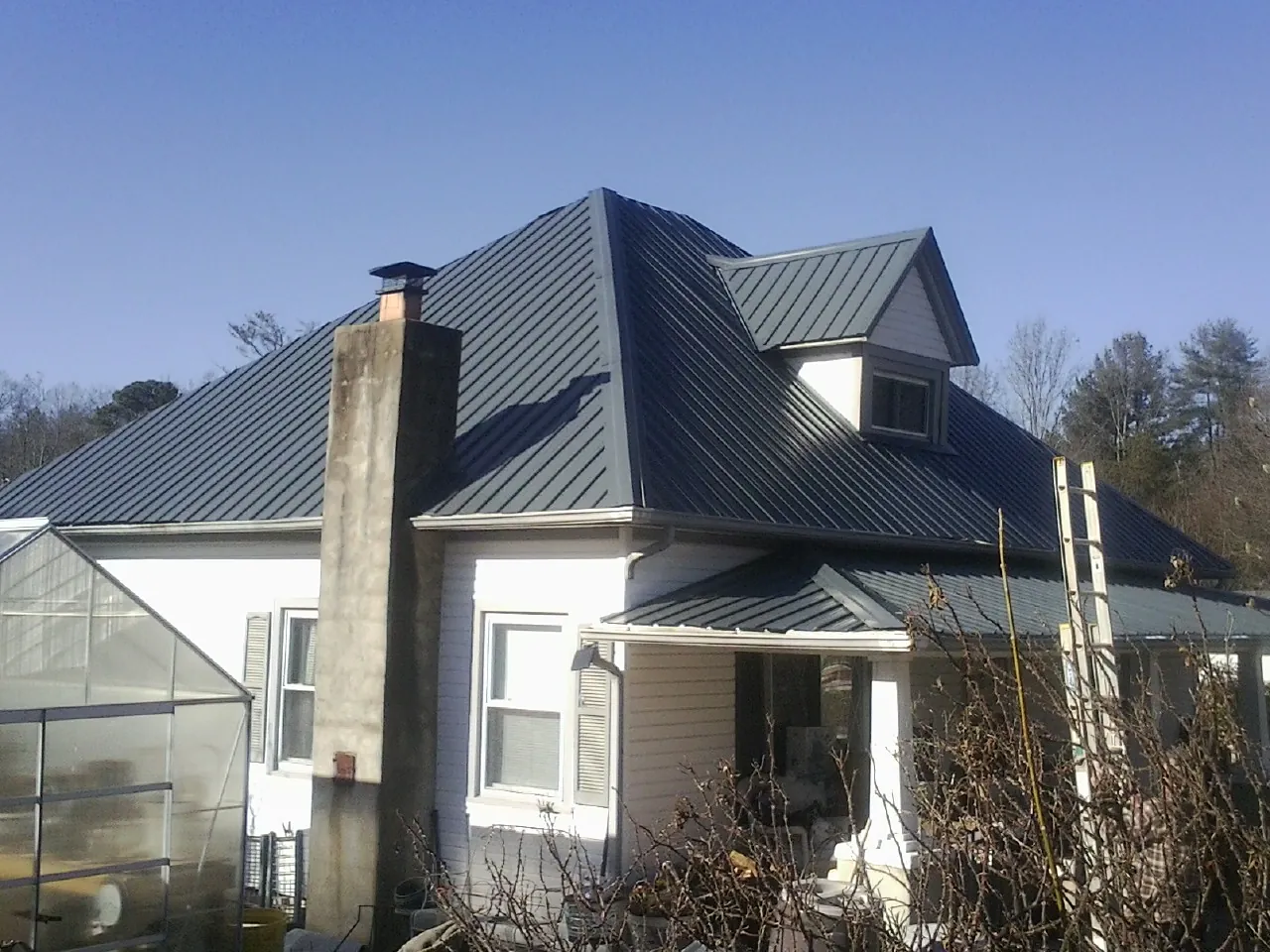 Dark blue standing seam metal roof on a white farmhouse with dormer — Slate & Tile Roof Repair by Roofing Brothers in Pleasant Prairie