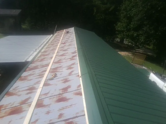 Old rusted panels beside newly installed green metal roofing — Wind Damage Roof Repair by Roofing Brothers in Pleasant Prairie