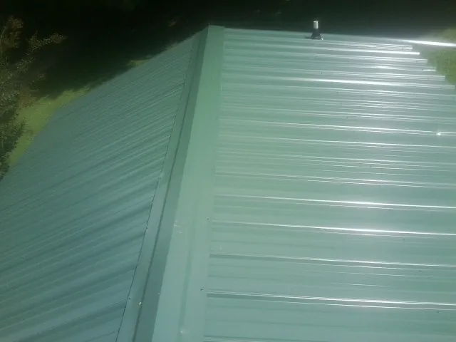 New green metal panels meeting at the ridge of a roof — Flat Roof Repair work by our crew in Pleasant Prairie