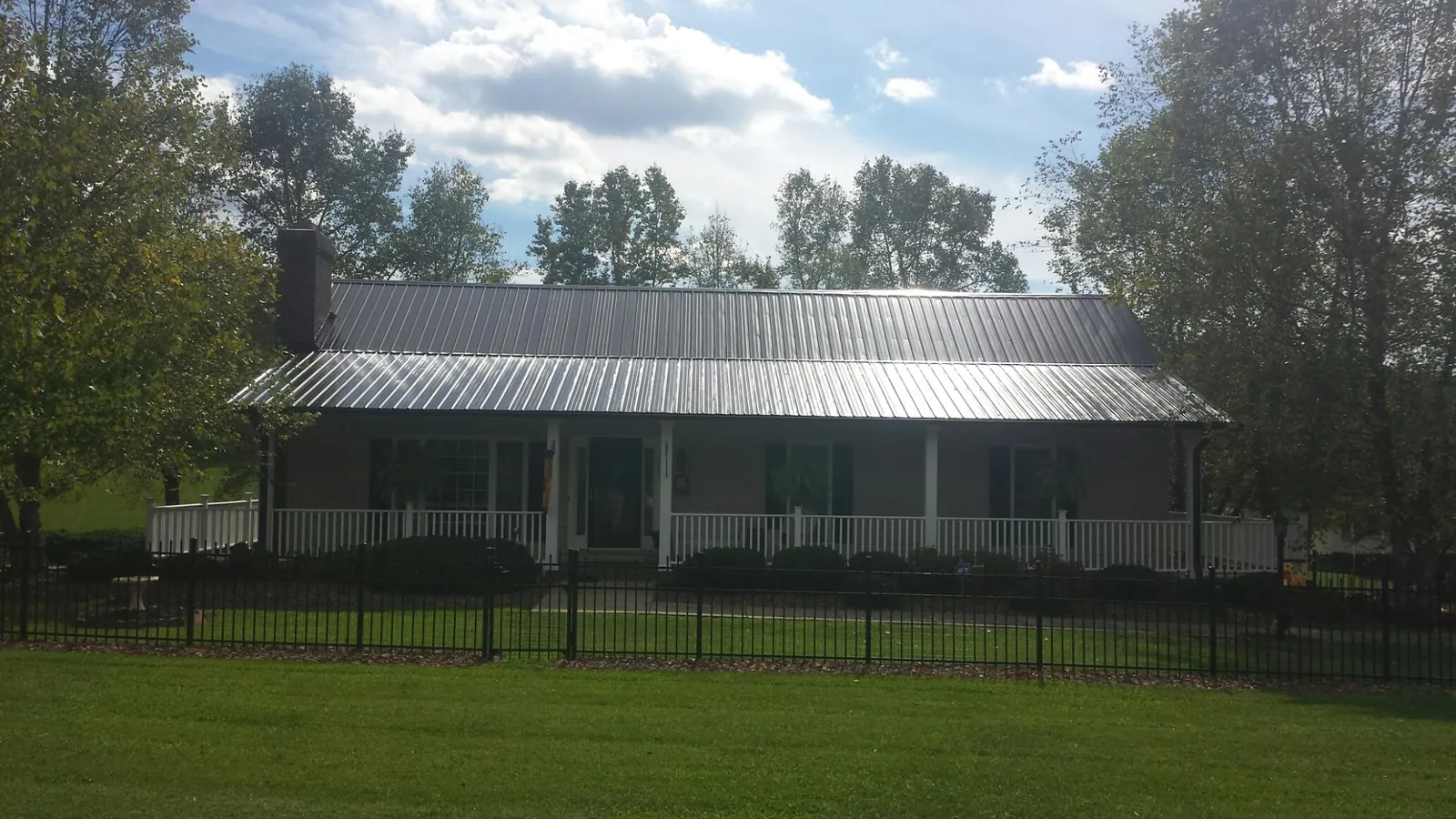 Gray metal roof on a brick ranch with a full width front porch — Gutter Guard Installation work by our crew in Pleasant Prairie