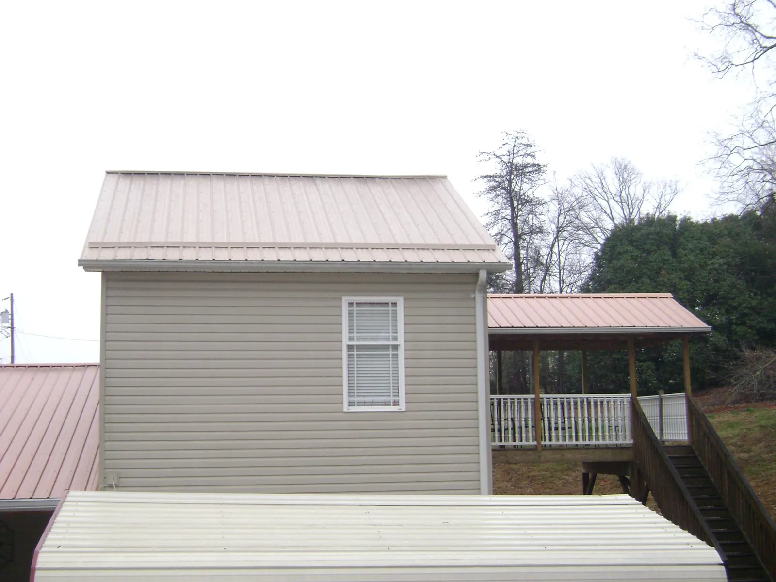 Tan metal roofs on a two story addition and attached porch, from a Roof Replacement job in Pleasant Prairie
