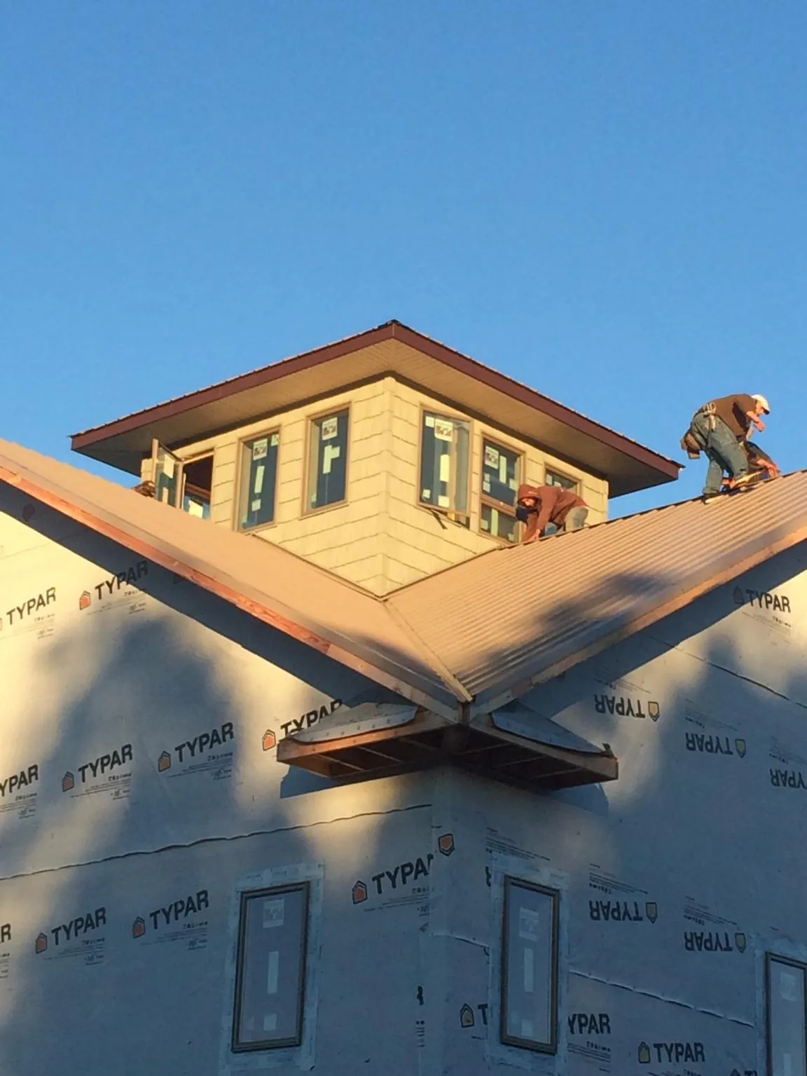 Roofers working around a rooftop cupola on a new metal roof at sunset — Roof Waterproofing in Pleasant Prairie by Roofing Brothers